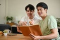 A smart Asian male college student is tutoring to his friend while studying at home together Royalty Free Stock Photo