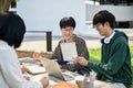 Smart young Asian male college student is tutoring math to his friends at a campus park Royalty Free Stock Photo