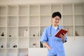 Smart young Asian male medical student reading a book while standing in a library Royalty Free Stock Photo