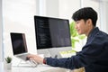 Smart young Asian male programmer coding at his desk, using laptop and computer Royalty Free Stock Photo