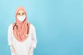 Smart young asian muslim woman doctor in lab coat with Medical face mask,white latex medical gloves and stethoscope against blue