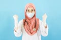 Smart young asian muslim woman doctor in lab coat with Medical face mask,white latex medical gloves and stethoscope against blue Royalty Free Stock Photo