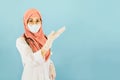 Smart young asian muslim woman doctor in lab coat with Medical face mask,white latex medical gloves and stethoscope against blue Royalty Free Stock Photo