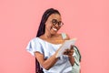 Smart young black woman with backpack writing in notebook over pink studio background. University education Royalty Free Stock Photo
