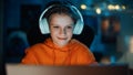 Smart Young Boy in Headphones Using Laptop Computer in Cozy Dark Room at Home. Happy Teenager Royalty Free Stock Photo