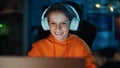 Smart Young Boy in Headphones Using Laptop Computer in Cozy Dark Room at Home. Happy Teenager Royalty Free Stock Photo
