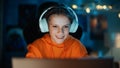 Smart Young Boy in Headphones Using Laptop Computer in Cozy Dark Room at Home. Happy Teenager Royalty Free Stock Photo