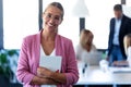 Smart young businesswoman looking at camera while holding her digital tablet on coworking place Royalty Free Stock Photo