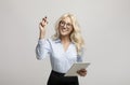 Smart young businesswoman with marker writing or drawing on virtual screen, standing against light grey background Royalty Free Stock Photo