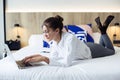 Smart young businesswoman working with her laptop lying on bed in the hotel room