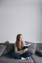 Smart young female sitting on the couch at home reading book, beautiful  woman with long hair Royalty Free Stock Photo