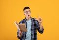 Smart young guy with book showing off his intelligence, gesturing eureka, having creative idea on orange background Royalty Free Stock Photo