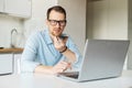 Smart young man sits at the kitchen desk and works remotely from home Royalty Free Stock Photo