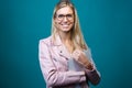 Smart young woman with eyeglasses looking at camera while holding digital tablet over blue background Royalty Free Stock Photo