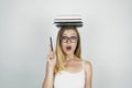 Smart young woman in glasses holding pen in her hand and books on her head isolated white background Royalty Free Stock Photo