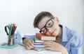 Smart youngster in eyeglasses putting his head on open book