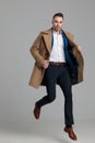 Smartcasual young guy wearing long coat and jumping