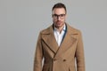 Smartcasual young man wearing long coat and glasses