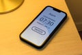 Smartphone alarm clock on bedroom night table with snooze button Royalty Free Stock Photo