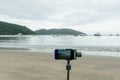 Smartphone attached to the gimbal filming the cloudy beach. Royalty Free Stock Photo