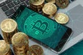 Smartphone with Bitcoin symbol on-screen laying on computer keyboard
