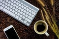 Smartphone with black blank screen, keyboard, coffee cup, dry grass flowers and roasted coffee beans on wooden texture background Royalty Free Stock Photo