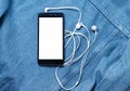 Smartphone with black case and a blank white screen and plugged in headphones ear buds on the background of denim Royalty Free Stock Photo