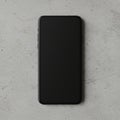 A smartphone with a black screen is placed on a light gray concrete surface. The Royalty Free Stock Photo