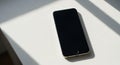 A smartphone with a black screen is placed on a white surface. Royalty Free Stock Photo