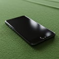 A smartphone with a black screen and sleek design lies on a textured green surface. Royalty Free Stock Photo