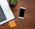 Smartphone with blank black screen and part of laptop keyboard on wooden desk Royalty Free Stock Photo