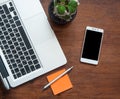 Smartphone with blank black screen and part of laptop keyboard on wooden desk Royalty Free Stock Photo