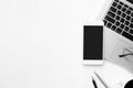 Smartphone with blank mock up screen is on top of white office desk table with laptop computer and supplies. Top view with copy Royalty Free Stock Photo