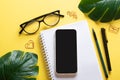 Smartphone, blank notepad, glasses, pen, paper clips, pencil on a yellow background. Blogging in the workplace is a Royalty Free Stock Photo