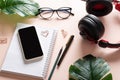 Smartphone, blank notepad, headphones, monster flower leaf, glasses, pen, paper clips, pencil on a light background, top Royalty Free Stock Photo