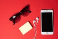 Smartphone with Blank Screen Connects to Earphones with Spiral Cable on Red Background Top View, Sunglasses