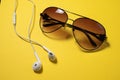 Smartphone with Blank Screen Connects to Earphones with Spiral Cable on yellow Background Top View, Sunglasses