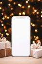 Smartphone with blank screen, gifts and bokeh on background Royalty Free Stock Photo