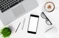 Smartphone with blank screen, laptop, coffee cup, glasses, pen and pencil on white office desk table, top view, workspace design, Royalty Free Stock Photo