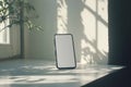Smartphone with blank screen placed on a white surface near a window with natural light and shadows Royalty Free Stock Photo