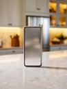 Smartphone with blank screen standing on marble countertop in modern kitchen with warm lighting and blurred background for home Royalty Free Stock Photo