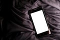 Smartphone with a blank white display on a folded satin black background Royalty Free Stock Photo