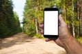Hand holding smartphone with white screen in forest road background. route Royalty Free Stock Photo