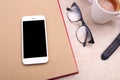 Smartphone on book with glasses and coffee on wooden background Royalty Free Stock Photo