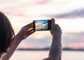 Smartphone camera in tourist woman personÃ¢â¬â¢s hands who taking photo on touch screen of beautiful seascape sky with clouds Royalty Free Stock Photo