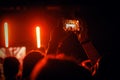 Smartphone capturing concert under orange stage lighting Royalty Free Stock Photo