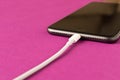 Smartphone on charge . On a purple background. Close up Royalty Free Stock Photo