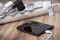 Smartphone and chargers connected to electrical power strip. Various devices charging concept