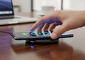 A smartphone charges wirelessly on a charging pad placed on a Royalty Free Stock Photo