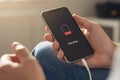 Smartphone charging at 10% battery, held in hand with cable connected, screen showing low power and charging status. Royalty Free Stock Photo